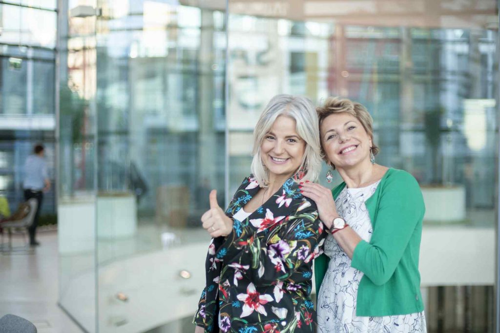 Izabela Pajor i Magda Kos razem na zdjęciu na tle szklanego biurowca
